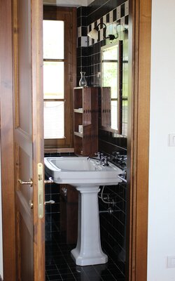 Weißes Waschbecken in schwarz verfliestem Badezimmer