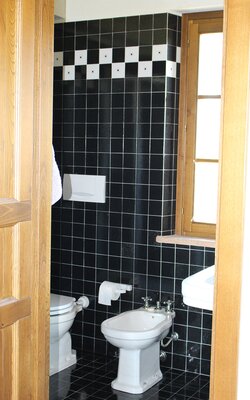 Badezimmer mit WC und Bidet und schwarzen kleinen Fliesen