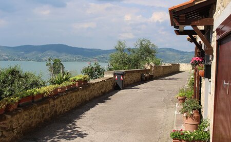 Kleine Straße entlang des Lago Trasimeno mit Blumentrögen entlang der Mauer 